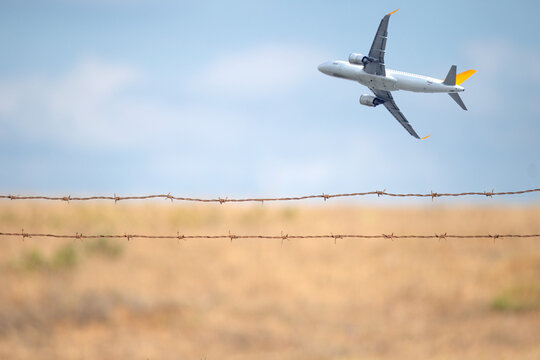 Passenger plane taking off behind wire fence. Concept of cross border or international travel. Aviation. Airport runway safety barrier. Deported. Copy space, blank, empty. 