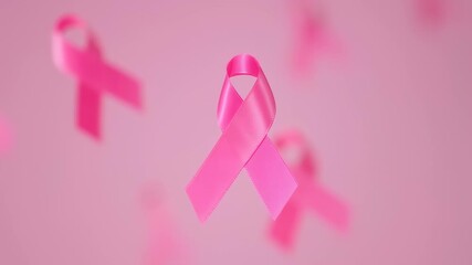 A pink awareness ribbon floating against a soft pink background. Other faint ribbons blur