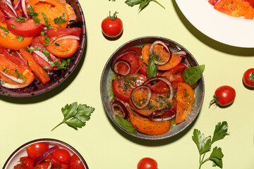 Bowls of fresh tomato salad with red onion and parsley on yellow background