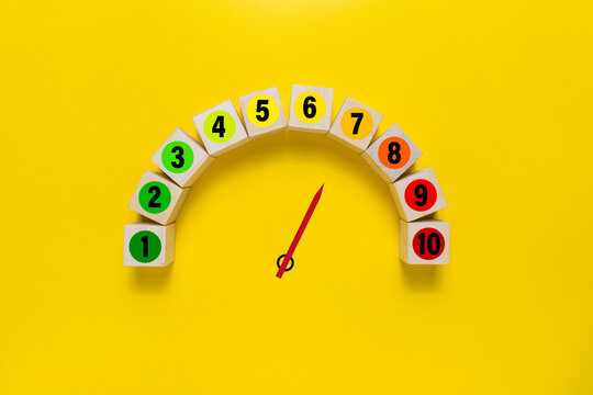 risk level meter indicator from low to high with 1 to 10 scale numbers on wooden blocks isolated on yellow background. concept of risk management - Powered by Adobe