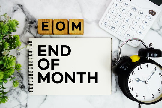 EOM End of Month text with calculator and alarm clock on marble background