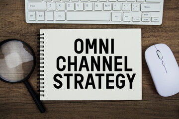 Omnichannel Strategy text written on notepad with keyboard, optical mouse and magnifying glass on wooden background