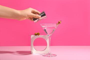 Female hand with shot and glass of tasty martini cocktail on pink background