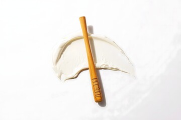 Abstract Still Life: Wooden Stick Piercing Cream Blob on White Background