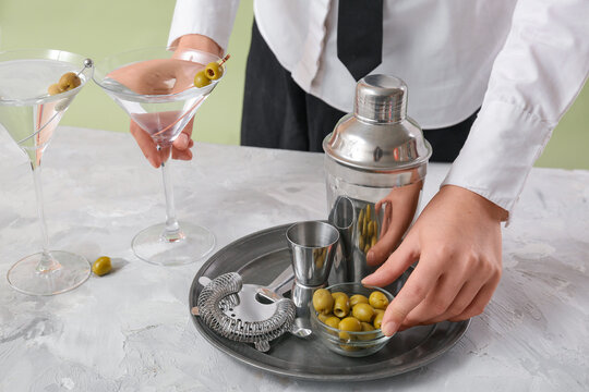 Female bartender making tasty martini cocktail at light table, closeup - Powered by Adobe