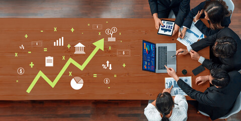 A group of business professionals engages in a strategic meeting, analyzing trends and discussing growth opportunities using various digital devices in a modern office setting. Trope