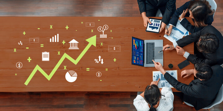 A group of business professionals engages in a strategic meeting, analyzing trends and discussing growth opportunities using various digital devices in a modern office setting. Trope