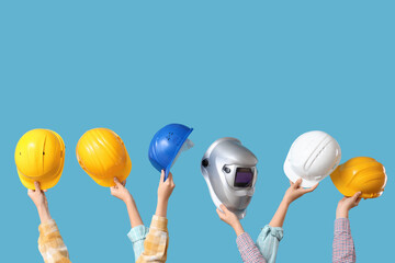 Hands with hardhats and welding mask on blue background