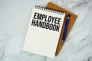 Employee Handbook text written on notepad with pen on marble background
