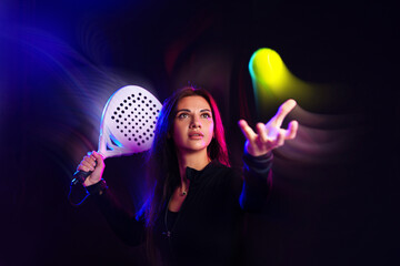 Woman playing padel tennis with a racket in a colorful light setting