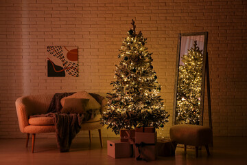 Comfortable sofa, Christmas tree, floor mirror and pouf in interior of dark living room