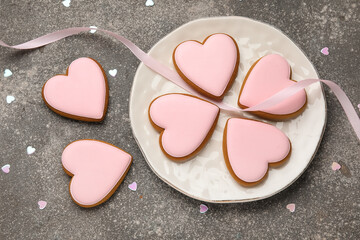 Plate with sweet heart-shaped cookies and ribbon on dark background. Valentine's Day celebration