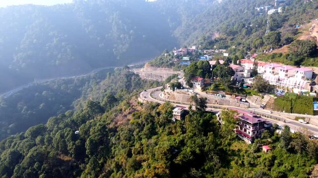 Drone footage capturing the scenic Chandigarh-Shimla Highway and solan valley in the Himalayan foothills, features cars and trucks moving along the winding asphalt road, flanked by dense green forests