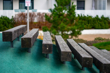 Wooden terrain steps on green playground surface surrounded by vegetation within modern residential housing estate outdoor area