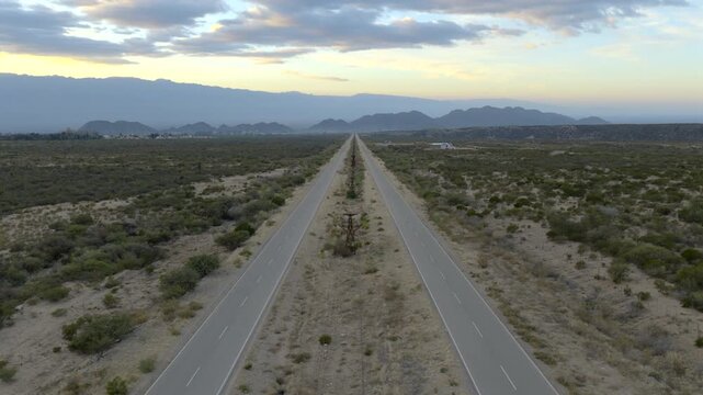 Beautiful sunrise at long straight desert highway stretching endlessly toward distant mountains, Av. la Mexicana, Chilecito, La Rioja Province, Argentina