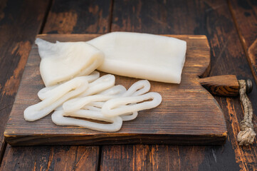 White fresh calamari ring displayed on rustic board with herbs ideal for seafood recipes menus and professional food photography.