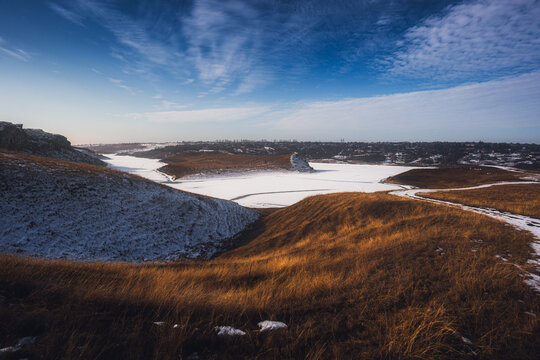 Scenic winter landscape with snow-covered river valleys under a partly cloudy blue sky