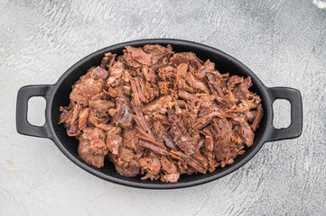 Tender slow cooked venison and elk stew with herbs in a cast iron dish on a light textured background for rustic gourmet food concepts.