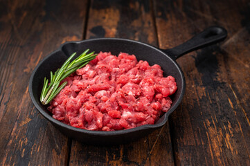Raw chopped beef veal meat with herbs in black skillet over bright surface perfect for recipe design culinary ads and protein rich visuals.
