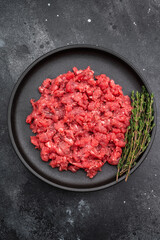 Ground lamb mutton on black dish against textured dark backdrop great for kitchen prep visuals high quality food photography and stock content.