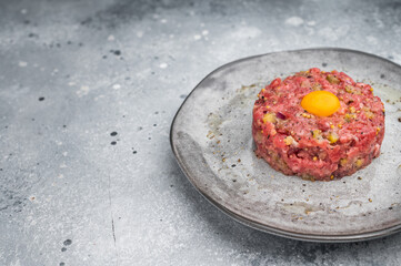 Fresh beef tartare with yolk on stone dish and wooden board great for gourmet cooking protein rich meals and high quality food photography.