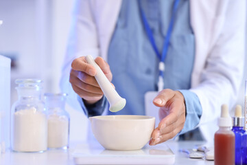 Young African-American female chemist with mortar and pestle working in lab, closeup