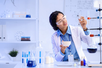Pretty young African-American female chemist with mortar and test tube working in lab