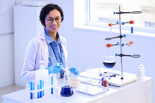 Pretty young African-American female chemist with mortar and Petri dish working in lab