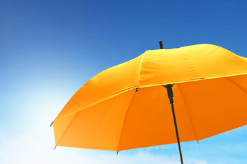 Closeup of yellow umbrella with blue sky