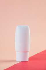White cosmetic product or sunscreen cosmetic with stylish props on light orange background.