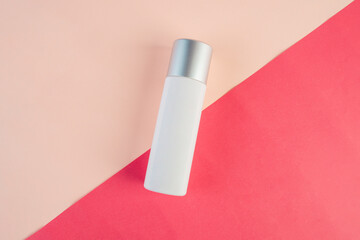 White cosmetic product or sunscreen cosmetic with stylish props on light orange background.