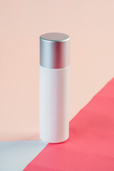 White cosmetic product or sunscreen cosmetic with stylish props on light orange background.