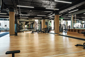 Modern gym interior with wooden flooring and various workout equipment in use
