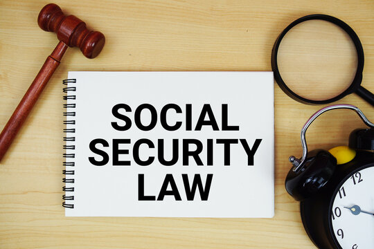 Social Security Law text written on notepad with pen, alarm clock and judge gavel on wooden background