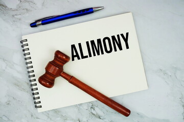 Alimony text written on notepad with pen and judge gavel on marble background
