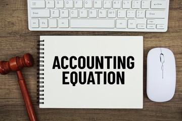 Accounting Equation text written on notepad with judge gavel, keyboard and optical mouse on wooden background