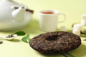 Dry pressed puer tea with teapot and cup on green background