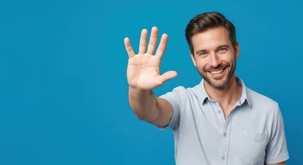 Fototapeta premium Smiling young caucasian male waving hand on blue background