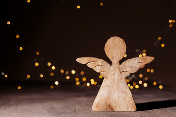 Fototapeta premium Rustic wooden angel figurine on holiday lights