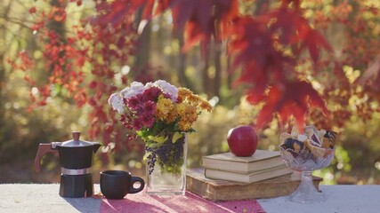 Autumn coffee scene outside. Fall mood on decorated table. Cozy outdoor autumn moment. Autumn table with books and apple. Warm fall treats on table. Cozy autumn tea break. Rustic fall table.