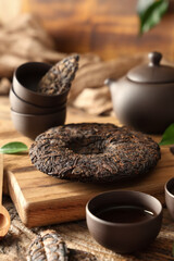 Dry pressed puer tea with teapot and cups on wooden background