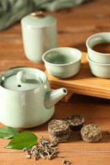 Tray with dry pressed puer tea, teapot and cups on wooden background