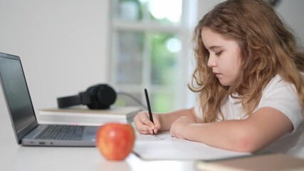 Child studying with laptop. Kid learning online at home. Focused child doing homework. Kid writing in notebook. Online school for kids. Child watching lesson on laptop. Kid studying at desk. - Powered by Adobe