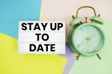 Stay Up To Date text in lightbox with alarm clock on pastel background