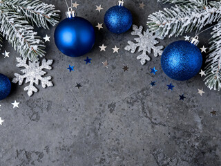 Blue and silver festive decorations on dark textured concrete background with pine branches frame