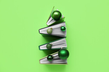 Christmas tree made of different books and balls on green background