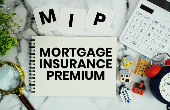 MIP Mortgage Insurance Premium text written on notepad with house model, calculator, magnifying glass and alarm clock on marble background