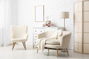 Interior of stylish room with armchairs and Christmas tree made of books on chest of drawers