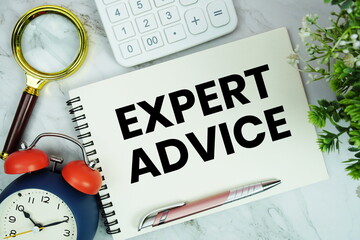 text written on notepad with alarm clock, magnifying glass and calculator on marble background