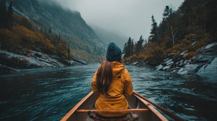 Solo paddler navigating a serene river through a misty mountain landscape.